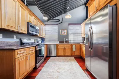 a kitchen with wooden cabinets and a stainless steel refrigerator at Long Beach Apartment - 10 Min Walk to the Beach! in Long Beach