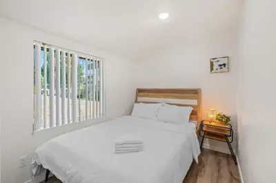 a white bedroom with a bed and a window at Foothills LA Hideaway Patio Lounge Work-Friendly in Glendora