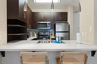 a kitchen with a large white counter with two chairs at Great 2bd 2bath in MdR! Free parking and pool! in Los Angeles