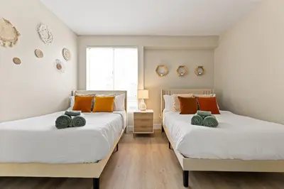 two twin beds in a bedroom with white and orange pillows at Great 2bd 2bath in MdR! Free parking and pool! in Los Angeles