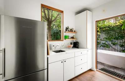 a kitchen with white cabinets and a large window at Abbot Kinney 2-Story Bungalow with Sauna and Plunge in Los Angeles