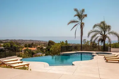 a swimming pool with chairs and palm trees and the ocean at Malibu Coastal Paradise with Pool, Spa and Tennis Court in Malibu