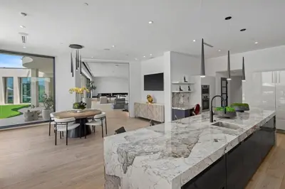 a kitchen and living room with a large marble counter top at Prestigious 6BR BH Mansion W. Pool, Theatre, Views in Los Angeles