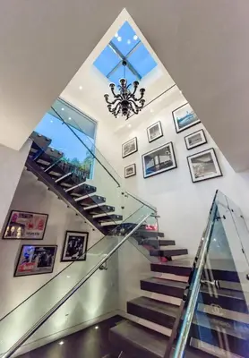 a staircase with a glass rail and a chandelier at Royalty Villa in Beverly Hills in Los Angeles