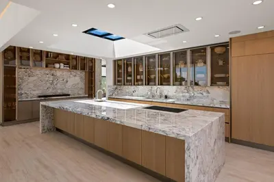 a kitchen with a marble counter top and wooden cabinets at Ultra Luxurious 5BR Villa W. Pool, Jacuzzi, Views in Los Angeles