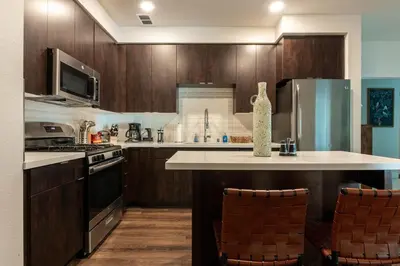a kitchen with wooden cabinets and a counter with chairs at Cozy and Calm Retreat in Heart of Glendale in Glendale
