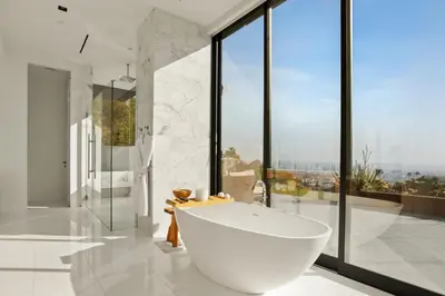 a bathroom with a large white tub and large windows at Belfast Estate in Los Angeles