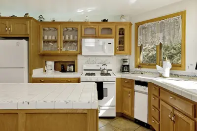 a kitchen with wooden cabinets and white appliances at The Village Timber Lodge at Big Bear - Downtown Log Cabin Retreat in Big Bear Lake