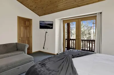 a bedroom with a bed and a couch and a television at The Village Timber Lodge at Big Bear - Downtown Log Cabin Retreat in Big Bear Lake
