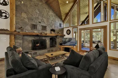 a living room with couches and a stone fireplace at The Village Timber Lodge at Big Bear - Downtown Log Cabin Retreat in Big Bear Lake