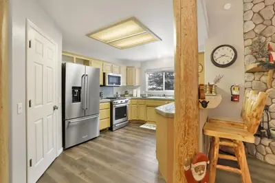 a kitchen with a stainless steel refrigerator and yellow cabinets at Modern Relaxation at Castle Glen Gem Big Bear Lake in Big Bear Lake