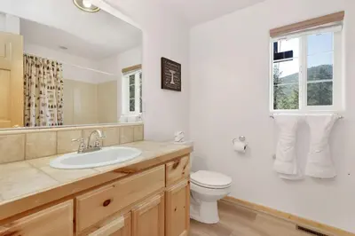 a bathroom with a sink and a toilet and a window at Lookout Lodge Family Chalet at Big Bear w/ Games in Big Bear City
