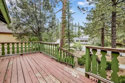 a wooden deck with a fence and trees at Pines & Needles Mountain Retreat by Big Bear Vacations in Big Bear Lake