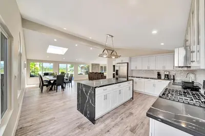 a large kitchen with white cabinets and a dining room at Incredible View, Huge Pool & Basketball! in Tarzana