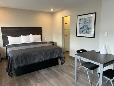 a bedroom with a bed and a desk and a table at Cloud 9 Inn - El Ciello Inn in Pico Rivera