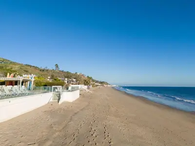 a sandy beach with white chairs and the ocean at Aquareve in Malibu Beach