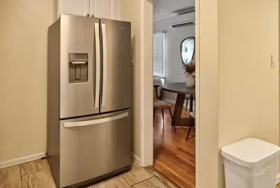 a stainless steel refrigerator in a kitchen with a table at Cozy Modern 2BR 1BA near LAX, LMU, SoFi Stadium and the Beach in Los Angeles