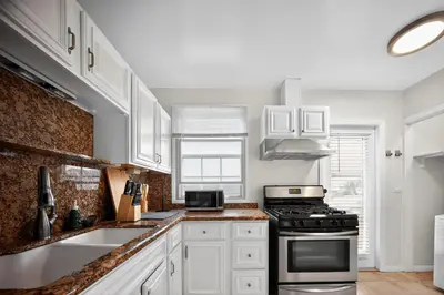 a kitchen with white cabinets and a stove top oven at Stylish LAX Area 2BR 1BA by LMU, SoFi Stadium & Coastal Beaches in Los Angeles