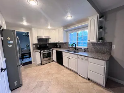 a kitchen with white cabinets and a sink and a refrigerator at Bright & Spacious 5BR Modern Vacation Home - Near Disneyland & Beaches in Orange