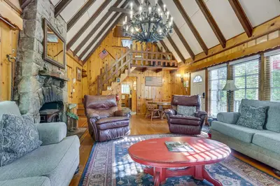 a living room with a stone fireplace and a table at Private Dock on Lake Arrowhead! Cozy Mtn Cabin in Lake Arrowhead