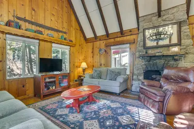 a living room with a couch and a stone fireplace at Private Dock on Lake Arrowhead! Cozy Mtn Cabin in Lake Arrowhead