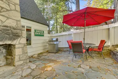 a patio with a table and chairs and an umbrella at Private Dock on Lake Arrowhead! Cozy Mtn Cabin in Lake Arrowhead