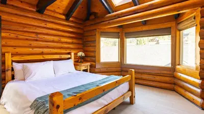 a bedroom with a bed in a log cabin at Arkouda Stays in Big Bear Lake