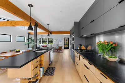 a kitchen with a black counter top and wooden cabinets at Brooks Beach House Your Venice Escape in Los Angeles