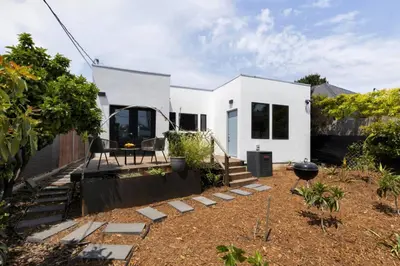 a white house with a garden and a patio at Brooks Beach House Your Venice Escape in Los Angeles