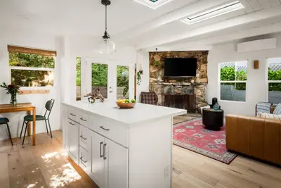 a kitchen with white cabinets and a living room at Laurel Canyon Hideaway Fireplace and Sauna in Los Angeles