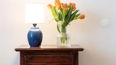 a vase of orange tulips and a lamp on a table at Sunny Venice Beach Home with Open Living Walkability to Abbot Kinney Venice Drift by AvantStay in Los Angeles