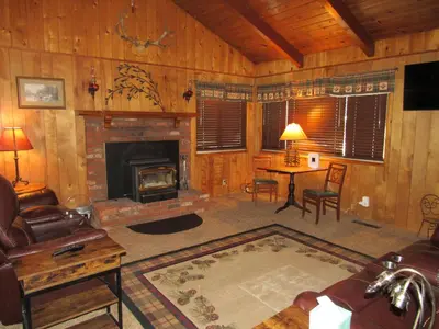 a living room with a fireplace and a table at M & M Sweet Retreat in Big Bear Lake