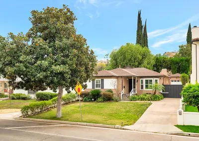 a house on a street with a tree and a yield sign at Charming 3BR with Ping-Pong and Spa!