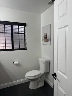 a white bathroom with a toilet and a window at Woodsy Chic Family-Friendly Spacious Getaway in Lake Arrowhead