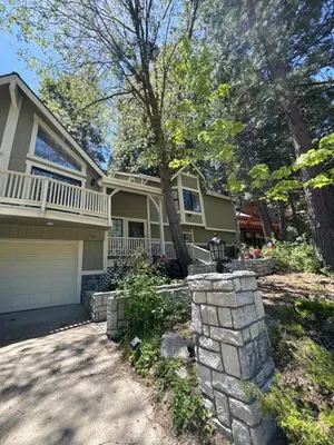 a house with a stone wall in front of a driveway at Woodsy Chic Family-Friendly Spacious Getaway in Lake Arrowhead
