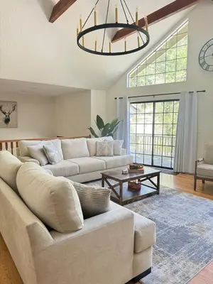 a living room with a large couch and a chandelier at Woodsy Chic Family-Friendly Spacious Getaway in Lake Arrowhead