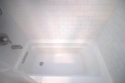 a white bath tub in a white tiled bathroom at Charming 1-bedroom apartment in amazing Palms, Los Angeles with AC, Parking in Los Angeles