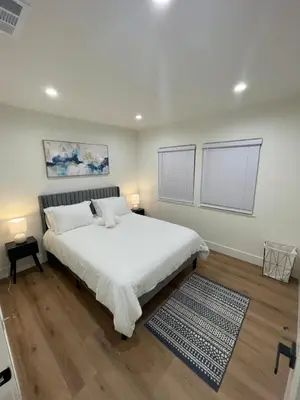 a bedroom with a large white bed and two windows at 2 bedroom Cozy house in heart of Burbank in Burbank