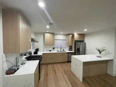 a large kitchen with white counter tops and wooden cabinets at 2 bedroom Cozy house in heart of Burbank in Burbank
