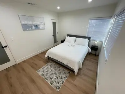 a bedroom with a bed with white sheets and a rug at 2 bedroom Cozy house in heart of Burbank in Burbank
