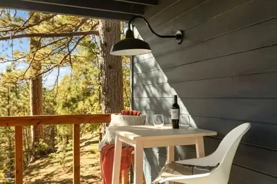 a table and chairs on a porch with a lamp at Lumiere Cabin in Lake Arrowhead