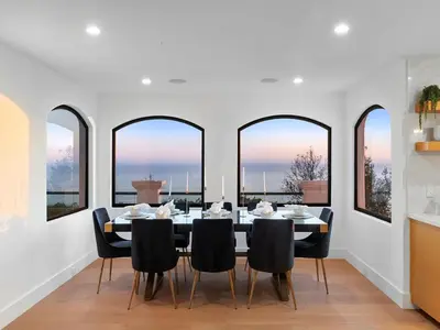 a dining room with a table and chairs and windows at Villa Costera in Malibu Beach