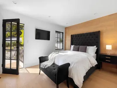 a bedroom with a large bed and a black chair at Villa Costera in Malibu Beach