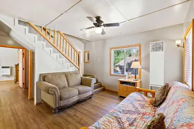 a living room with a couch and a staircase at Bear Creek Resort in Big Bear Lake