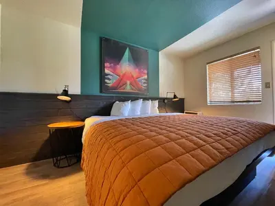 a bedroom with a large bed and a painting on the wall at Sessions Retreat & Hotel in Big Bear Lake