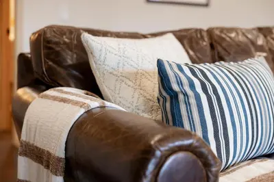 a brown leather couch with pillows on it at View On the Rocks Scenic Mountain Oasis with Hot Tub, Fire Pit and Game Room in Big Bear Lake