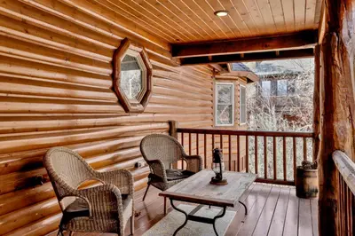 a cabin with a table and chairs on a porch at View On the Rocks Scenic Mountain Oasis with Hot Tub, Fire Pit and Game Room in Big Bear Lake