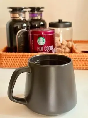 a black coffee cup sitting on a counter with a tray of food at Hillside Haven - Boutique Spanish Escape in Ojai