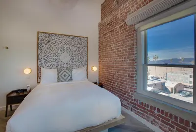 a bed in a room with a brick wall and a window at Venice V Hotel in Los Angeles