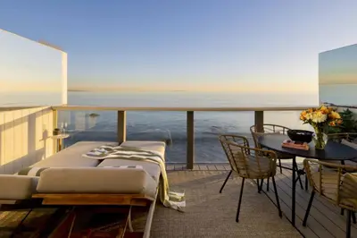 a balcony with a bed and a table and the ocean at Malibu Breeze in Malibu Beach
